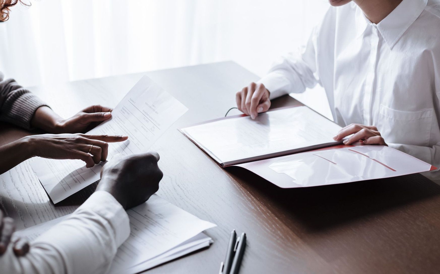 A diverse group of adults reviewing documents during a meeting at an office table.